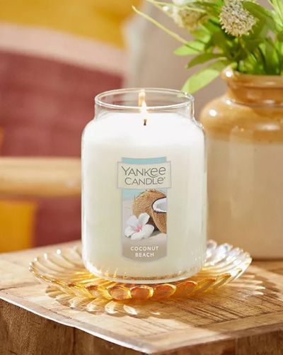 Bougie Yankee Candle 'Coconut Beach' allumée sur un plateau en verre.